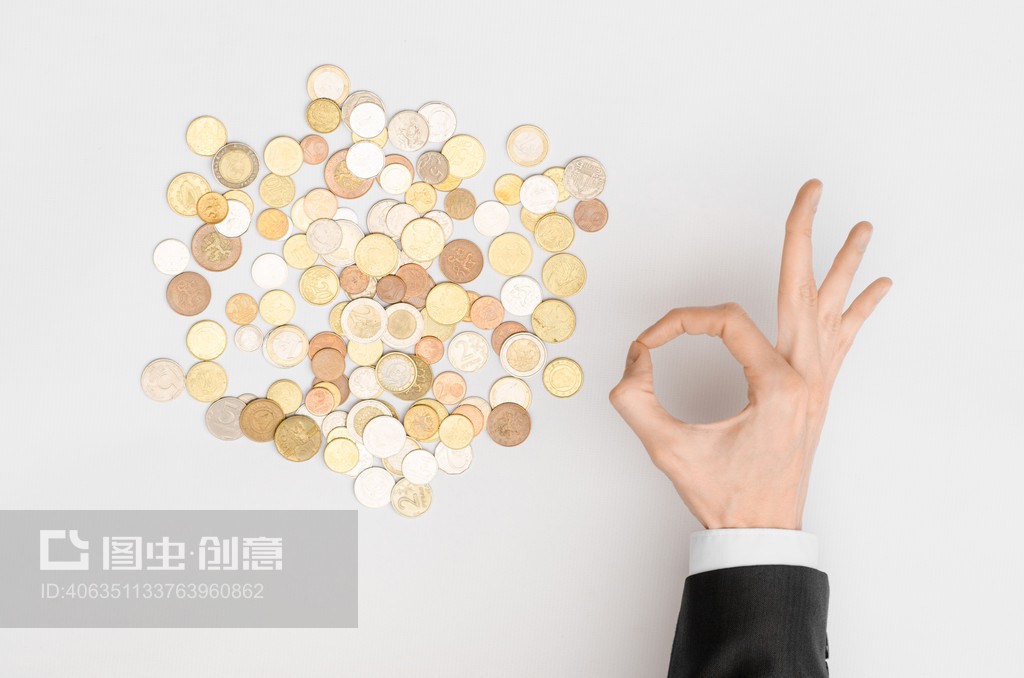 货币与金融主题:货币硬币和穿着黑色西装的人手在灰色背景俯视图上显示手势Money and Finance Topic: Money coins and human hand in black suit showing gesture on a gray background top view